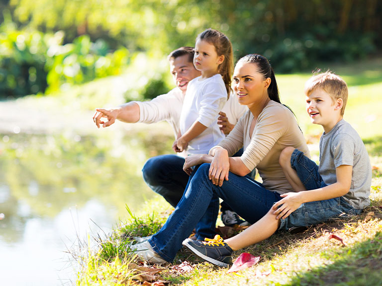 Eine Familie sitzt am Flussufer im Schatten